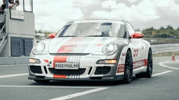Sports car drives on racetracks, surrounded by clouds and obstacles.