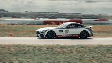 A race car drives fast on a racetrack with grass.