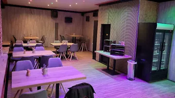 Moderne Tische und Stühle in einem beleuchteten Café.