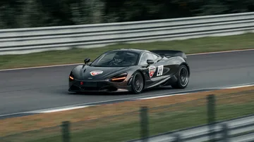 Ein schwarzes Sportauto fährt schnell auf einer Rennstrecke.