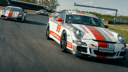 Race cars drive fast on a racetrack with trees.