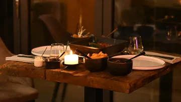Table with food, candle, glasses in a romantic setting.