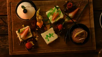 Dessert plate with various delicacies on a wooden base.
