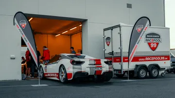 Sportwagen parkt an einer Garage, umgeben von Veranstaltern.