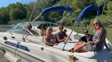 Boat on water, group of women pose happily.