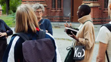 Group talks outdoors; one person explains something passionately.