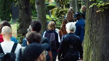 Group of people walking between trees in a cemetery.