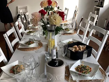 Table with food, drinks and flowers in a room.