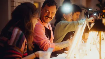 Groups of people talk at the table while working creatively.