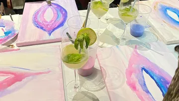 Glasses with cocktails are on the table; painting is created.