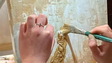 Hands painting textured gold canvas