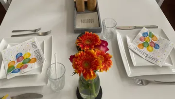 Tisch dekoriert mit Blumen und Geburtstagservietten.