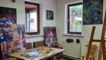 Colourful paintings hang on walls in a studio.