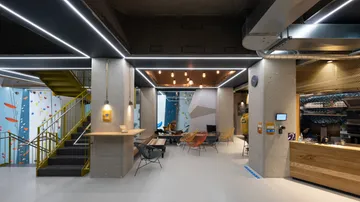 Moderne Kletterhalle mit Sitzbereichen und hellen Lichtern.