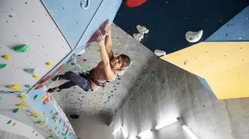 Kletterer bewegt sich an einer vertikalen Kletterwand in Halle.