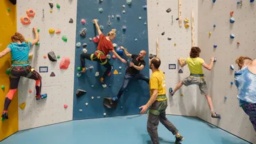 Kletterer nutzen verschiedene Wände in einer Kletterhalle.