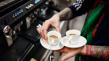 Two espresso cups are held by one person.
