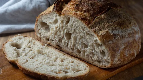 A loaf of bread is sliced on a wooden board.
