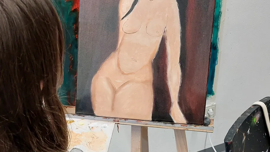 Artist paints naked model in a studio.