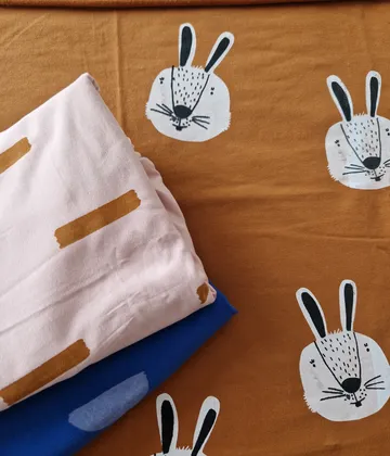 Bunte Stoffe mit Hasenmotiven liegen auf einem Tisch.