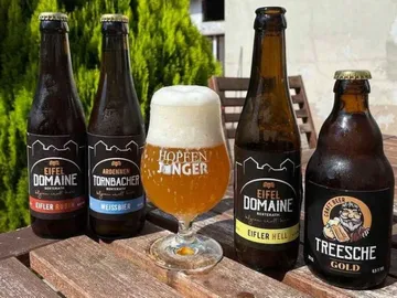 Bierflaschen stehen auf Tisch, Glas mit Bier in der Sonne.