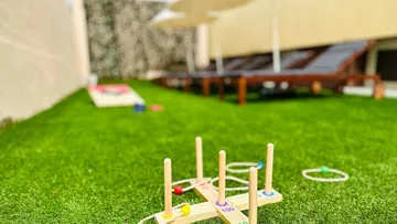 Holzspielzeug steht auf grünem Rasen, umgeben von Liegen.