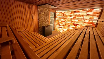 Holzsauna mit Trennwand, Sitzbänken und Salzsteinwand.