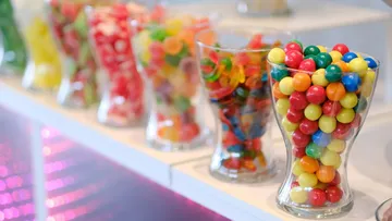 Colourful candies in jars arranged on a shelf.