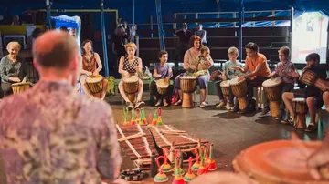 Trommelgruppe spielt rhythmisch im Zirkuszelt mit Instrumenten.