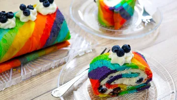 Colorful rainbow cake on plates, decorated with cream.