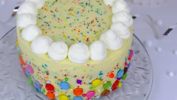Bunte Torte mit Sahne und Streuseln auf einem Teller.