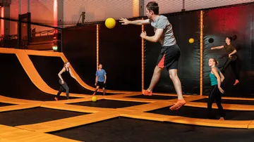 Trampolinpark: Menschen springen und spielen mit Bällen.