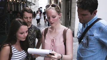 Four people are looking at a map on a busy street.