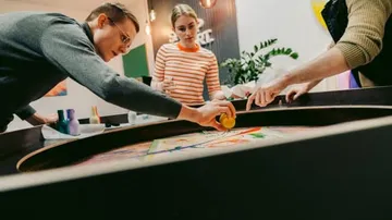 Drei Personen gestalten gemeinsam an einem runden Tisch.
