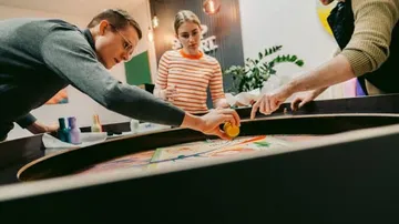 People paint colors on a round canvas in a creative space.