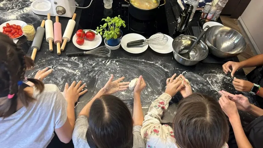 Children prepare dough in a kitchen with ingredients.