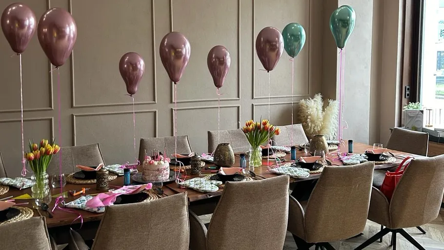 A festively decorated table with balloons and flowers.