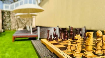 Chessboard with pieces in the garden, sun loungers in the background.