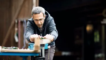 Mann arbeitet konzentriert an einem Holzprojekt in Werkstatt.