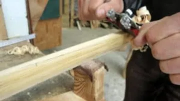 Holz wird mit einer Hobelmaschine bearbeitet, Werkstattumgebung.