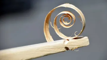 A wood chip spirals onto a workpiece.