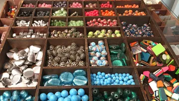 Colourful beads and jewelry arranged in wooden boxes.