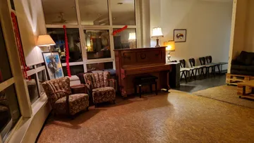 Zwei Sessel stehen vor einem Klavier in einem Raum.