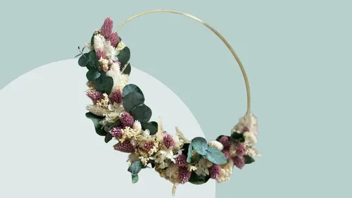 Blumenkranz hängt in der Luft, vor einfarbigem Hintergrund.