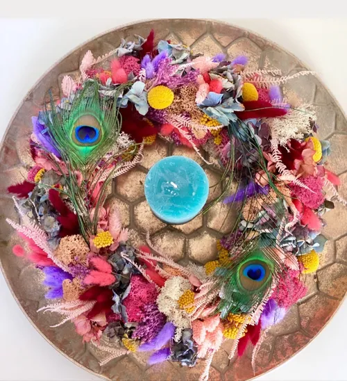 Colorful floral wreath surrounds a blue candle.