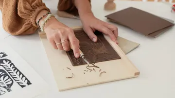 A hand carves into a brown plate on a table.