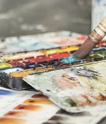 Pinsel färbt Aquarellfarben auf einer Palette, kreativ arbeiten.
