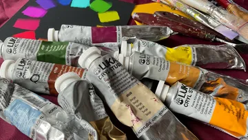 Acrylic paints in tubes are scattered on a table.