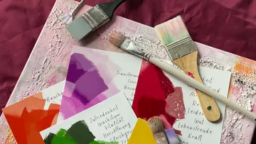 Paints and brushes lie on a messy canvas.