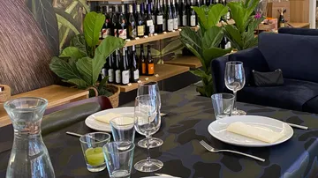 Tisch mit Geschirr, Gläsern, Pflanzen und Weinfregatten im Hintergrund.